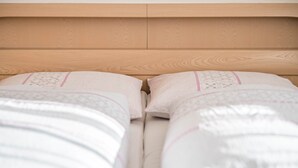 Un lit avec une tête de lit en bois et deux oreillers à motifs.