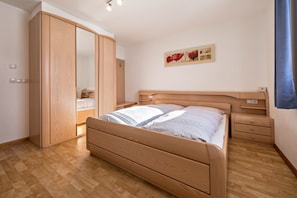 Une chambre à coucher avec un lit en bois, une armoire, une table de chevet et une œuvre d’art accrochée au mur.