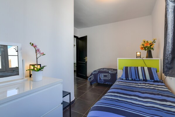 A bedroom with a bed, a bedside table, a TV, and a potted plant.