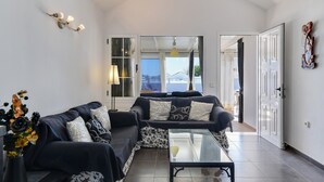 A modern living room with a sofa, a glass coffee table, and a decorative wall piece.