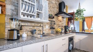 A kitchen with granite countertops, white cabinets, a built-in dishwasher, and a stone backsplash. - Holiday Home ‘Finca Alejandrina’ with Sea View, Pool, Garden & Wi-Fi (La Guancha)
