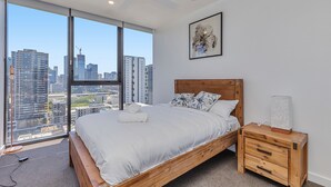A bedroom with a large bed, wooden headboard, and a nightstand with drawers. - KOZYGURU BRISBANE ONE 1Bed APT Parking (South Brisbane)
