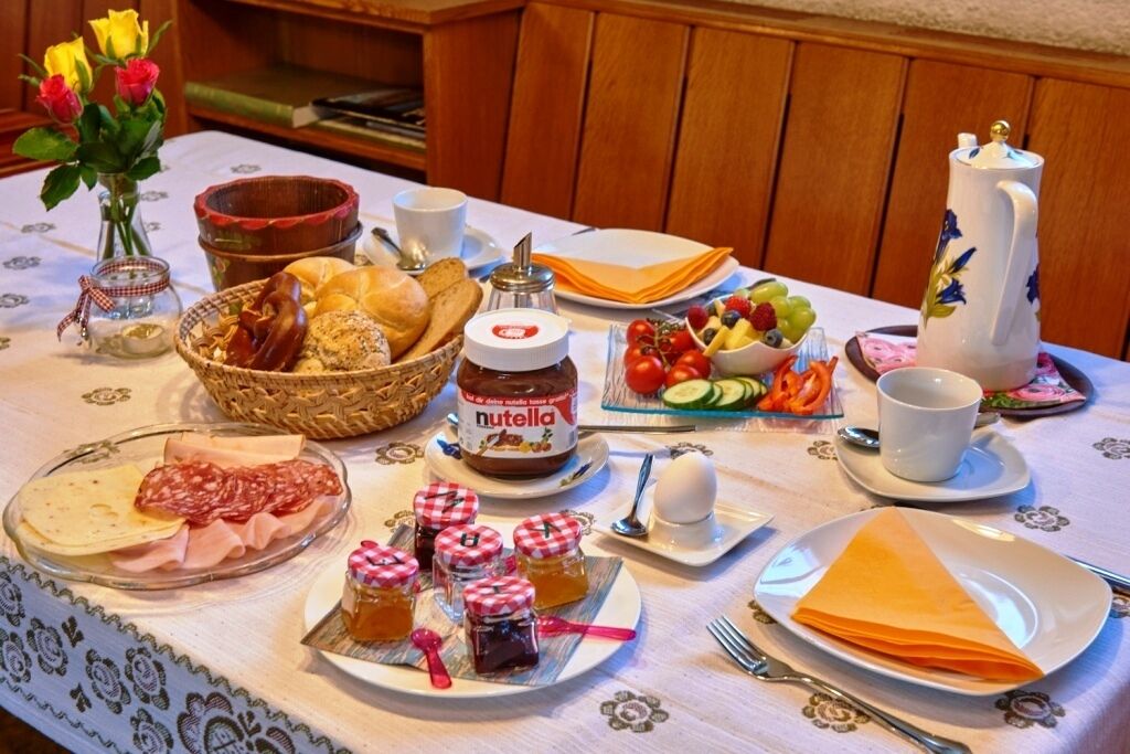 A breakfast table with various food items, including bread, pastries, and condiments.