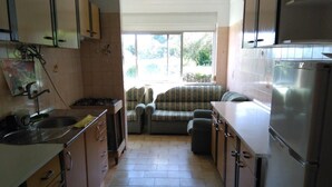 A compact kitchen with a dining area, a refrigerator, and a window providing natural light. - Apartment in the centre of Covilha (Covilha)