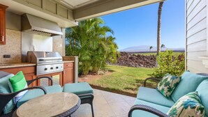 Un patio exterior con una parrilla, asientos y vistas del paisaje.