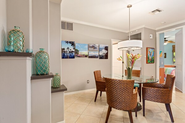 A dining area with wicker chairs, a glass table, and decorative vases.