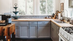 A kitchen with a window, wooden countertop, cabinets, and a stove.