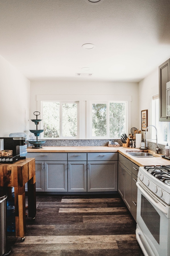 A kitchen with a window, wooden countertop, cabinets, and a stove.