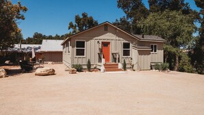 A single-story house with a red door, a front porch, and a small front yard.