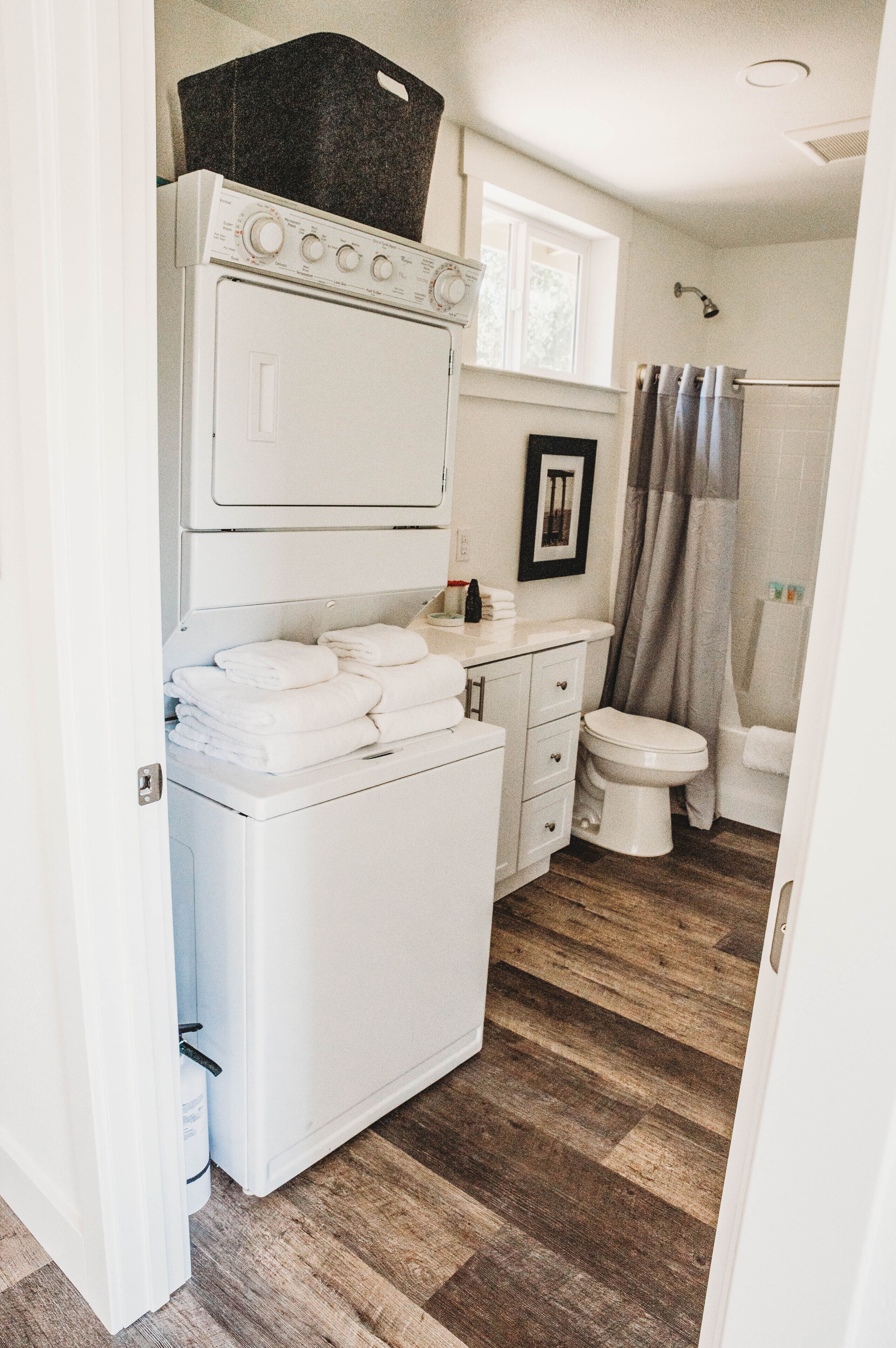 Un baño pequeño con lavadora blanca, inodoro y zona de ducha.