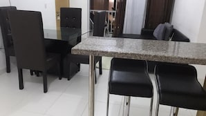 A dining area with a granite countertop, black chairs, and a dark wooden table.