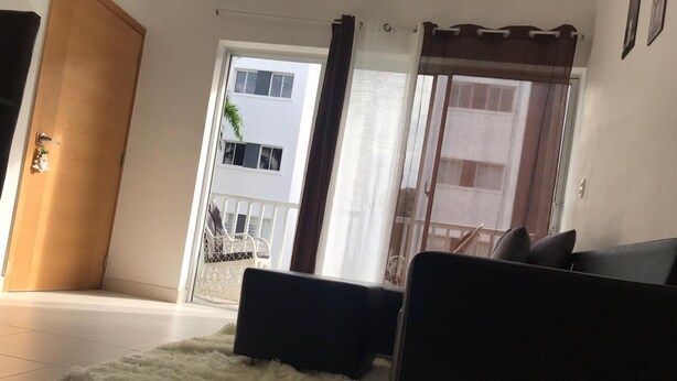 A living room with a sofa, a fluffy rug, and a sliding glass door leading to a balcony.