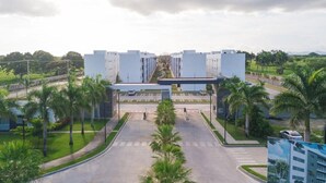 A modern building with a central entrance, surrounded by palm trees and a clear sky.