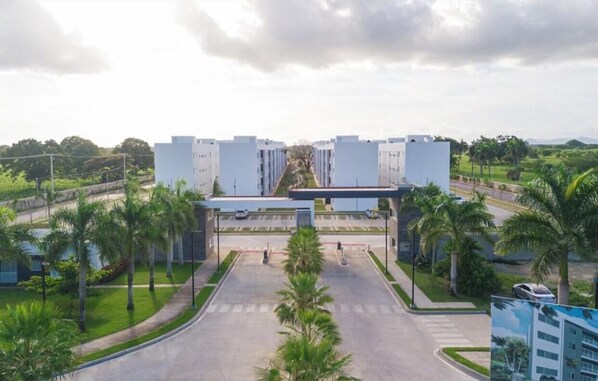 A modern building with a central entrance, surrounded by palm trees and a clear sky.