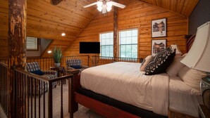 A bedroom with a wooden ceiling, a bed with white bedding, a ceiling fan, and two windows with blinds. - Inviting, Equestrian-Themed Cabin in the Very Heart of Branson! (Branson)