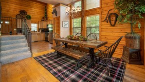A wooden interior with a dining table, benches, and a staircase. - Inviting, Equestrian-Themed Cabin in the Very Heart of Branson! (Branson)
