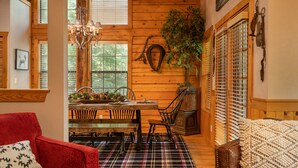 A cozy dining area with a wooden table, chairs, and a chandelier. - Inviting, Equestrian-Themed Cabin in the Very Heart of Branson! (Branson)