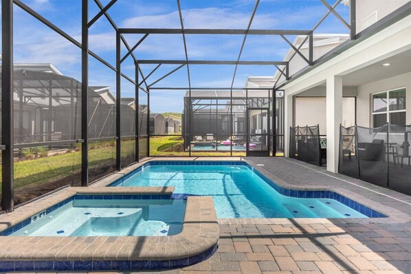 Relax by the pool surrounded by a lush lawn and a row of houses.