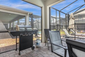 Relax in style with a barbecue grill and comfortable lounge seating, surrounded by a glass-enclosed patio with a beautiful view.