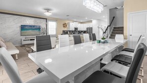 A modern kitchen with white cabinets, a central island, and a chandelier. - Dream Vacation Getaway next to Disney with Private Pool --10BD/5BA (Kissimmee)