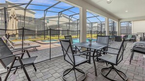 An outdoor patio with a pool, lounge chairs, and a table with chairs. - Dream Vacation Getaway next to Disney with Private Pool --10BD/5BA (Kissimmee)