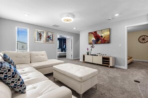 Relax in this spacious living room with a large sofa, matching ottoman, and flat-screen TV.