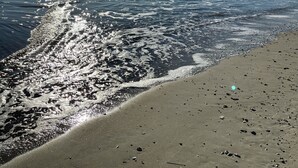 A beach with waves, a clear sky, and the sun shining. - Howards Haven (Bald Head Island)