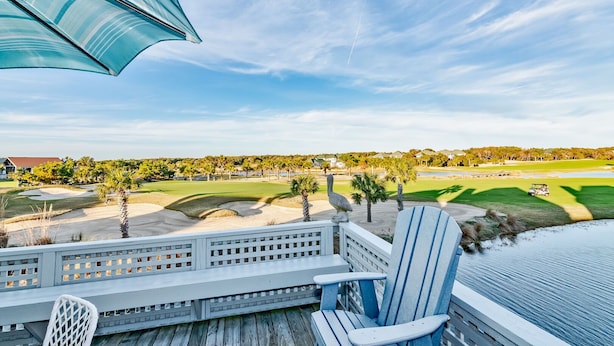 A deck with a view of a golf course, including sand bunkers and a pond. - Howards Haven (Bald Head Island)