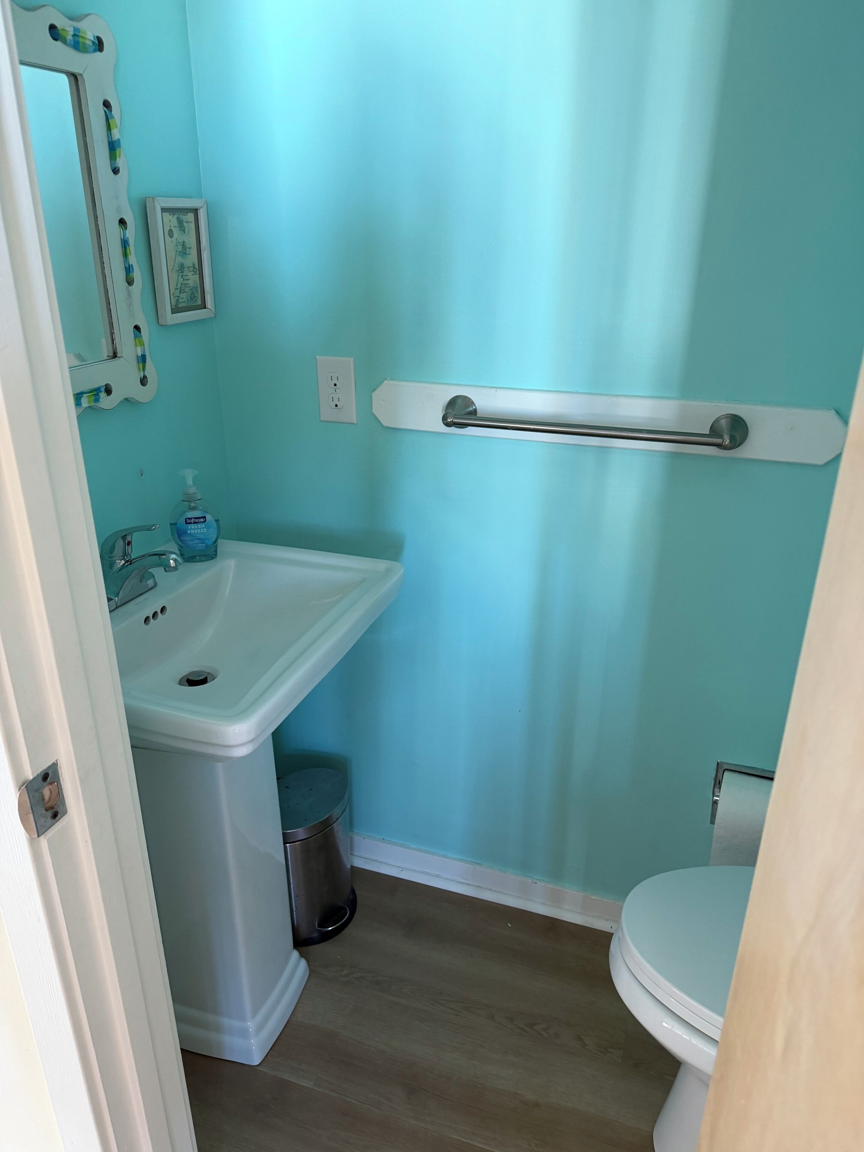 A bathroom with a sink, toilet, and a handrail.