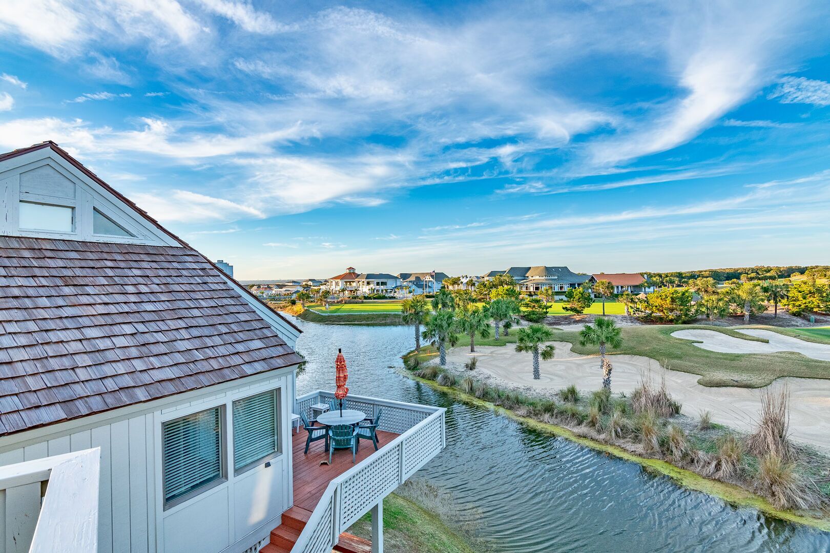A residential property with a balcony overlooking a water body and a golf course.