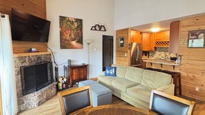 Una sala de estar acogedora con chimenea, un sofá y un televisor montado en la pared.