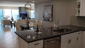 Una cocina moderna con encimera de granito, electrodomésticos de acero inoxidable y un comedor con vistas al balcón.