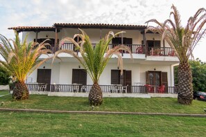 Un edificio de dos pisos con un balcón en el nivel superior, rodeado de palmeras.