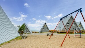 Een strand met een schommel en een gebouw met een schuin dak.