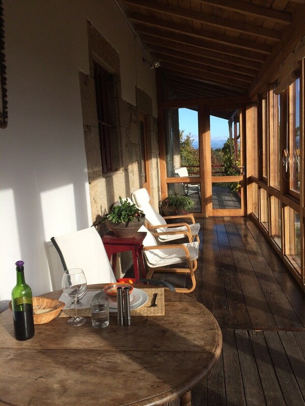 Eine Holzterrasse mit Tisch und Stühlen, einem Blumentopf und Blick auf die Landschaft.