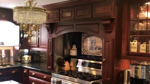 A kitchen with dark wood cabinets, a chandelier, a stove, and various kitchen appliances. - Majestic House on 23 acres with 5k feet of lakefront  (Fairfax)