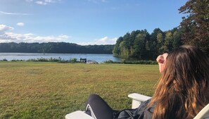 A person seated outdoors with a view of a lake and forested hills. - Majestic House on 23 acres with 5k feet of lakefront  (Fairfax)