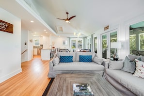 A spacious living room with a grey sofa, a wooden coffee table, and a ceiling fan. - Beautifully Remodeled Modern, Yet Charming Beach Home w/Ocean Views & Private Pool! Quiet Location! (Isle Of Palms)