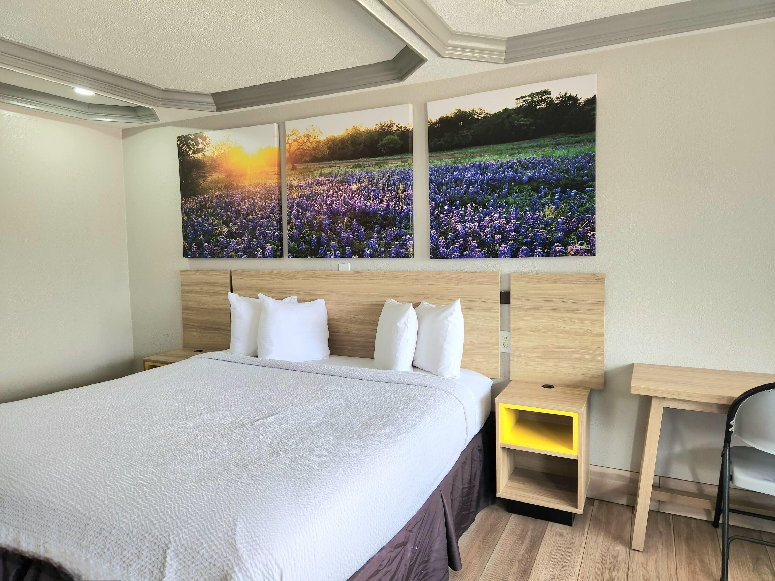 A bedroom with a large bed, a wooden headboard, a nightstand, and a desk.