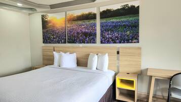 A bedroom with a large bed, a wooden headboard, a nightstand, and a desk.