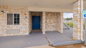 A stone building with a blue door, a guest laundry sign, and a handicapped parking sign. - Days Inn by Wyndham Kenedy/Karnes City (Kenedy)