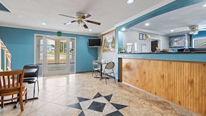 A reception area with a wooden counter, a ceiling fan, and a tiled floor with a geometric pattern. - Days Inn by Wyndham Kenedy/Karnes City (Kenedy)