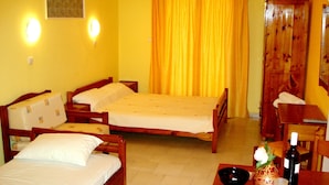 A room with two wooden beds, a wooden table with a vase and wine bottle, and a yellow curtain. - Finikas Apartments Polichrono (Kassandra)