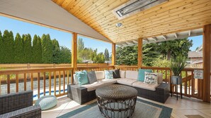 A covered patio with a wooden ceiling, outdoor furniture, and a view of trees and houses. - Luxury 8 beds Villa with Pool & Resort Amenities (Edmonds)