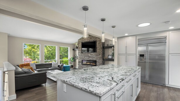 A modern kitchen with a large island, built-in appliances, and a stone fireplace. - Luxury 8 beds Villa with Pool & Resort Amenities (Edmonds)
