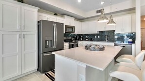 A modern kitchen with white cabinetry, stainless steel appliances, a central island with seating, and pendant lighting. - 2 Bedrooms / 2 Bathrooms / Storey Lake (3131-303 PC) (Kissimmee)
