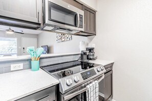 A modern kitchen with stainless steel appliances, including a microwave, stove, and oven. - Trendy SoCo 1BR suite, king bed, fast WiFi w/ pool (Austin)