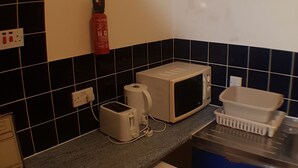 Una cocina compacta equipada con microondas, tostadora y un refrigerador pequeño.