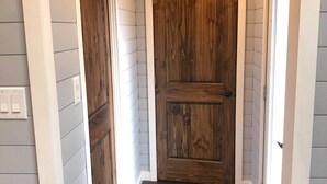 Un pasillo con puertas de madera y paredes revestidas de blanco.