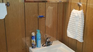A wooden-paneled bathroom with a sink, a mirror, and a towel hanging on the wall. - Week/ Weekend Cabin Rental #2 (Luther)